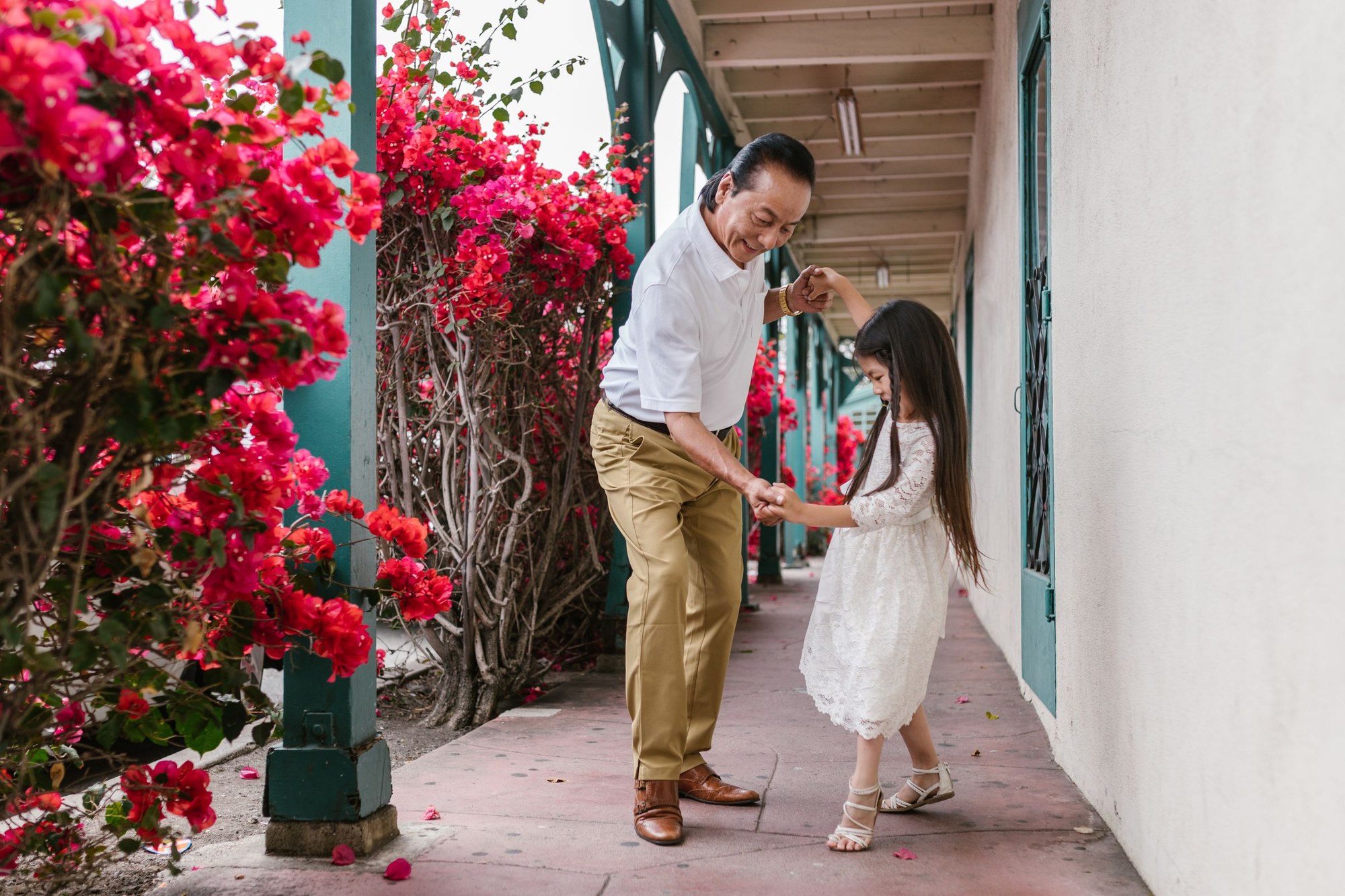 East Asian grandfather and granddaughter dancing outdoors
